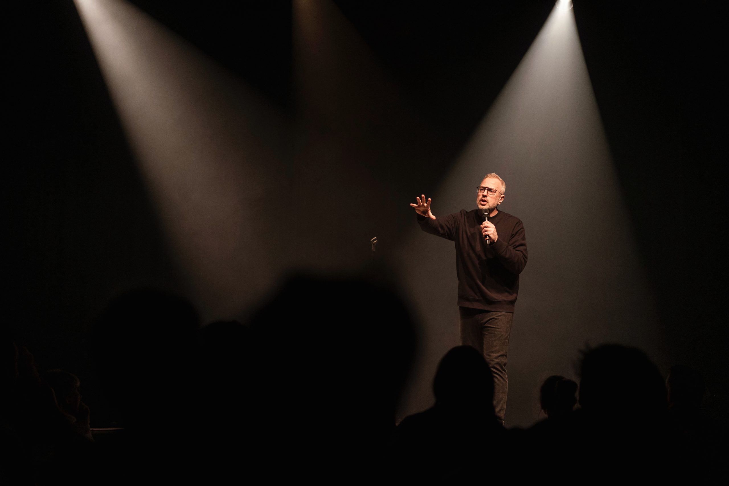 Conférencier parlant sur une scène sous un éclairage dramatique