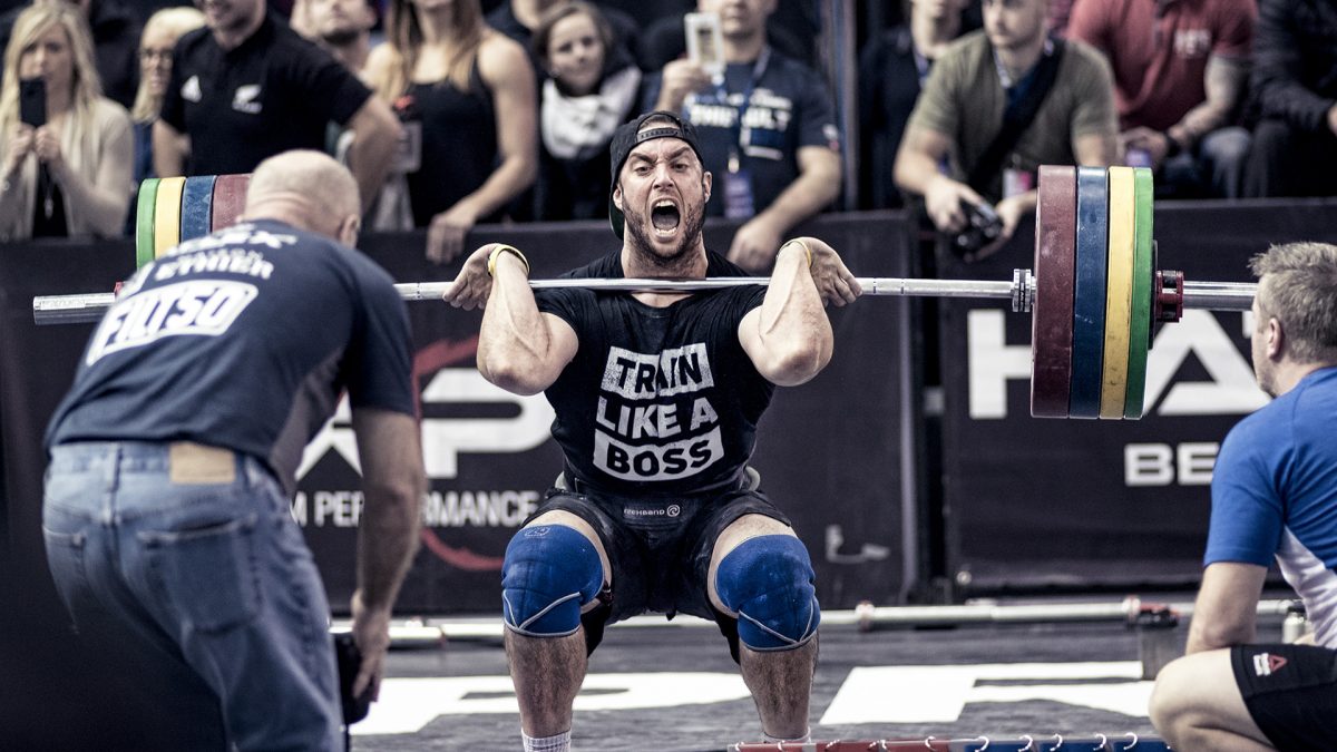 CrossFit and weightlifter doing a heavy squat clean at a competition