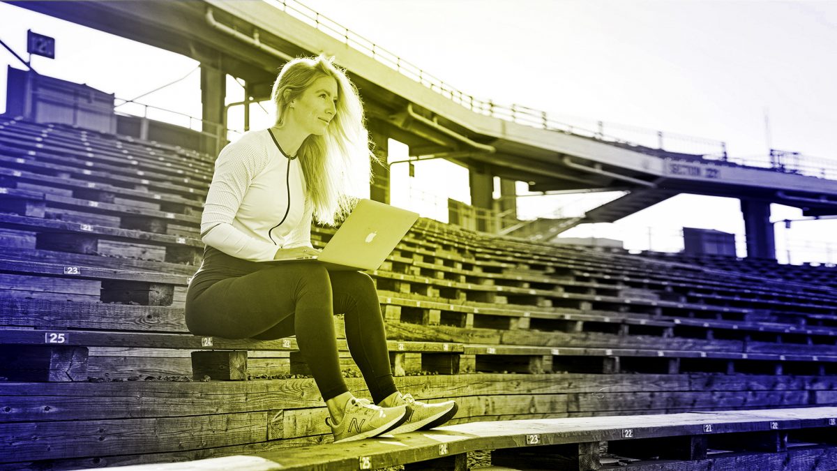 Coach athlete with computer sitting on bleachers