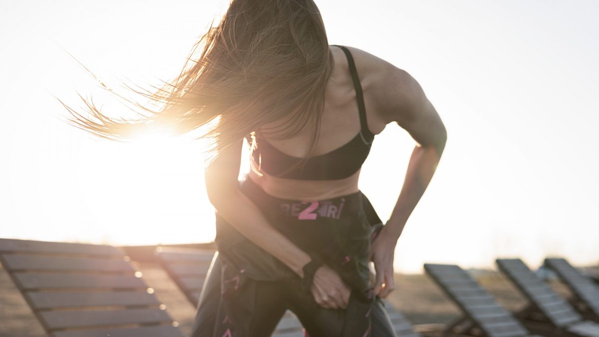 Triathlon athlete puts on trisuit with wind ans sun in her hair
