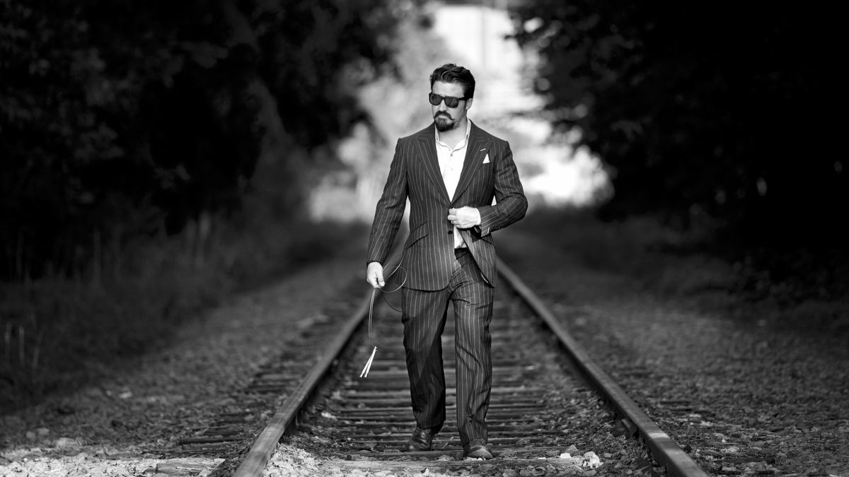 Black and white picture man walking on train rails
